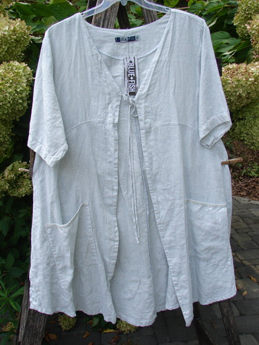 Barclay NWT Linen Contrast Tie Pocket Cardigan Field Twig Dew Size 0: A loose-fit, mid-length linen smock with short sleeves, front tie closure, and large pockets, displayed outdoors on a hanger.