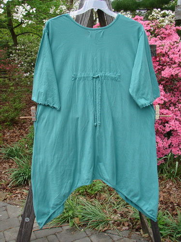 Barclay Three Quarter Sleeved Quad Pocket Tunic with a Scooped Neckline, Wide Sleeves, and Four Drop Pockets, hanging on a clothesline; featuring detailed forest garden theme paint.