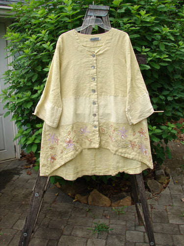 Barclay Linen Wonderland Sectional Banded Cardigan Daisy Chain Celery Size 1 displayed on a hanger, showcasing its unique horizontal panel design, belled sleeves, scooped neckline, and thick pearly buttons.