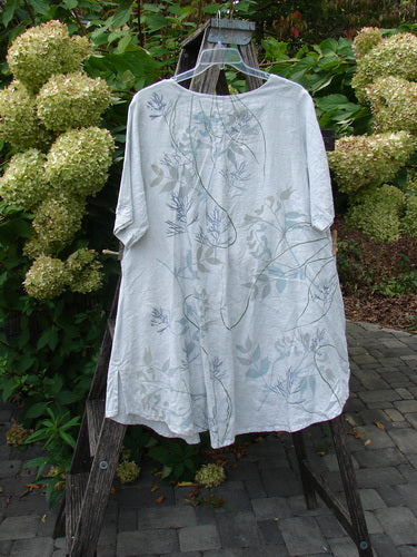 Barclay NWT Linen Contrast Tie Pocket Cardigan Field Twig Dew Size 0 draped on a transparent hanger, showcasing its loose fit and subtle botanical print against a garden backdrop.