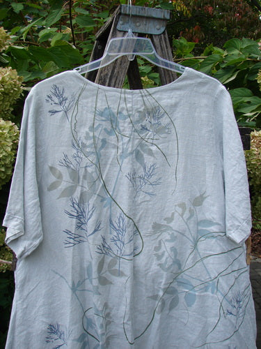 Barclay NWT Linen Contrast Tie Pocket Cardigan in Field Twig Dew Size 0 draped on a clear hanger over a wooden ladder, set against lush greenery, showcasing its loose fit and botanical print.