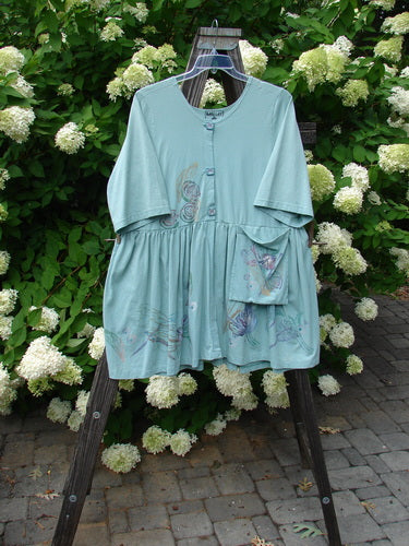Barclay Flower Garden Tunic Dress Dragonfly Aloe Size 2 displayed on a swing, featuring a three-button front, open lower front, pleated skirt, and painted pocket.