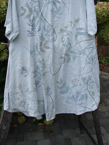 Barclay NWT Linen Contrast Tie Pocket Cardigan Field Twig Dew Size 0 hangs from a wooden frame, showcasing its botanical motif with slender vines and leaves in muted greens and slate blues.