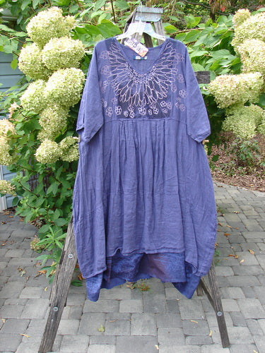 Barclay NWT Linen Process Two Story Dress Mum Ultra Violet Size 0 features a loose fit, knee-length design with floral embroidery on a purplish-blue fabric, displayed on a wooden ladder amidst garden foliage.