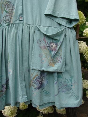 Close-up of Barclay Flower Garden Tunic Dress Dragonfly Aloe Size 2, showcasing a ceramic three-button front, open lower front, super full pleated skirt, and external painted floppy pocket.