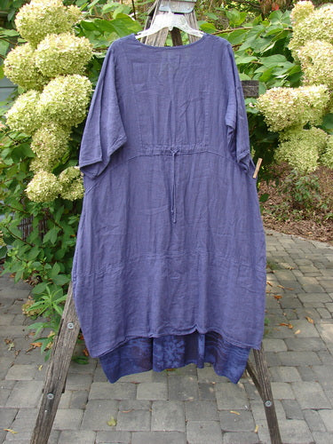 Barclay NWT Linen Process Two Story Dress Mum Ultra Violet Size 0, hangs on a rustic ladder, showcasing its loose fit and lightweight linen fabric, with a tag attached.