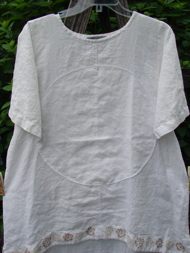 Barclay Linen Shirt Tail Top Circle Center Daisy Chain White Size 0 displayed on a rack, showcasing its vented hemline, rounded neckline, and unique center circle with daisy border design from Bluefishfinder.com.