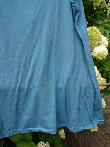A close-up of a blue shirt on a clothesline, featuring a diagonal insert and a front vertical neckline tie. Barclay NWT Batiste Decora Tiny Tank Unpainted Peacock Size 2.