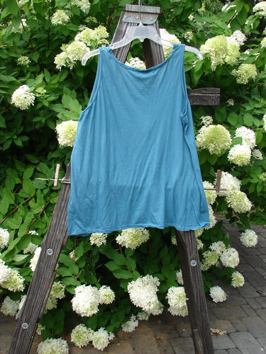 Barclay NWT Batiste Decora Tiny Tank Unpainted Peacock Size 2 displayed on a wooden ladder, showcasing its front vertical neckline tie and gather with a slightly A-line shape.