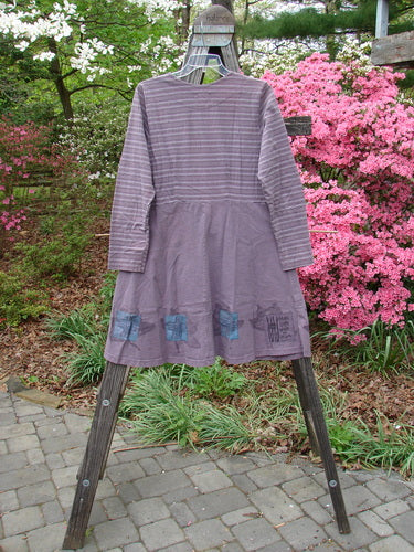 1999 Fitted Circle Dress with Dried Pod theme, Grey Plum Stripe pattern, size 0, featuring empire waist seams, flattened pleats, flared skirt, rounded neckline, and longer sleeves, displayed on a wooden rack.