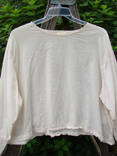 1999 Batiste Boxy Top Unpainted Natural Size 2 on a clothes hanger, showcasing its boxy shape, rounded neckline, and billowy sleeves, embodying the vintage style of Bluefishfinder.com’s unique collection.