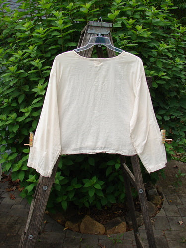1999 Batiste Boxy Top Unpainted Natural Size 2 displayed on a wooden ladder, showcasing its rounded neckline, boxy shape, and billowy sleeves in flowing cotton batiste fabric, exemplifying vintage elegance.