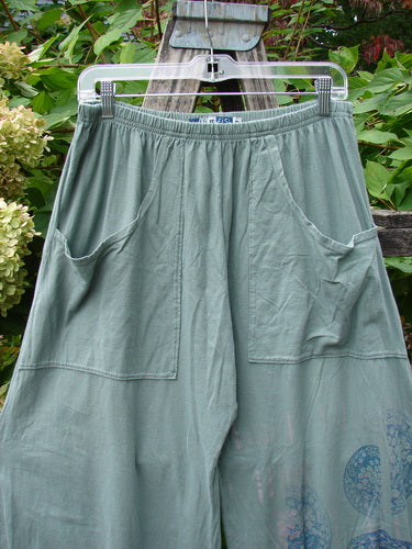 Barclay Flutter Bottom Crop Cargo Pant Medallion Vine Size 0, featuring a unique fluttered hem, elastic waistband, and square patch pockets, showcased against a garden backdrop, highlighting its artistic lower leg pattern.