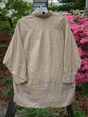 1996 Woven Tourist Top Farm Cow White Pine Gingham OSFA, long-sleeved shirt with wooden buttons, vented sides, and a stand-up collar, displayed hanging on a tree branch.