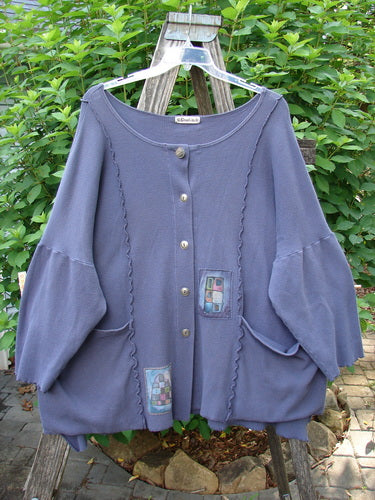 Barclay Patched Thermal Curl Pocket Cardigan in Geos Royal Orchid Size 3, featuring a full button front, dolman sleeves, and two front pockets, showcased on a swing outdoors.