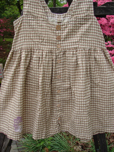 1996 Woven Roadside Jumper Flower Wheel White Pine Gingham Size 1, featuring wooden buttons, a pleated blousy lower, squared neckline, and sectional upper panels, displayed on a swing against an outdoor backdrop.
