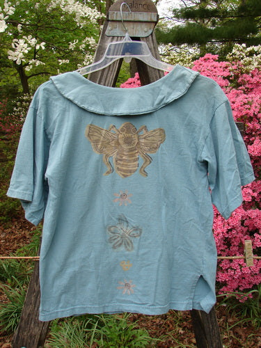 1994 Compass Top Garden Bee Dusk Size 1: A blue shirt featuring a large, pointed collar, bee-themed garden art, and original buttons, perfectly showcasing the vintage charm of Blue Fish Clothing.