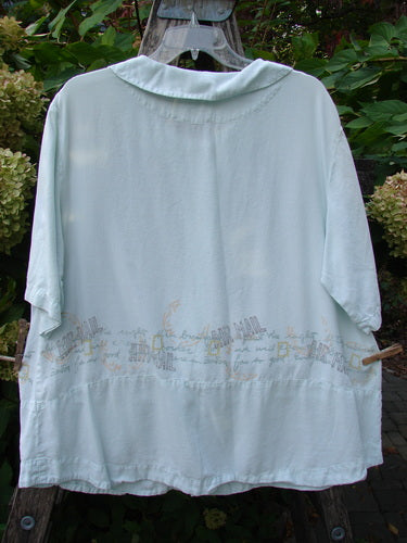 2000 Tencel Camp Shirt Airmail Shark Size 0 features a loose, short-sleeved design with subtle back embroidery, simple collar, and hangs on a ladder amidst greenery, reflecting Bluefishfinder's vintage aesthetic.