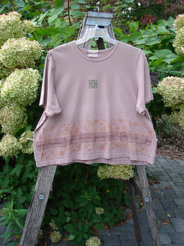 2000 Short Sleeved Crop Tee Floral Fence Border Coralline Size 2, featuring a subtle square chest graphic and musical-note motifs at the hem, draped over a wooden ladder in a garden setting.