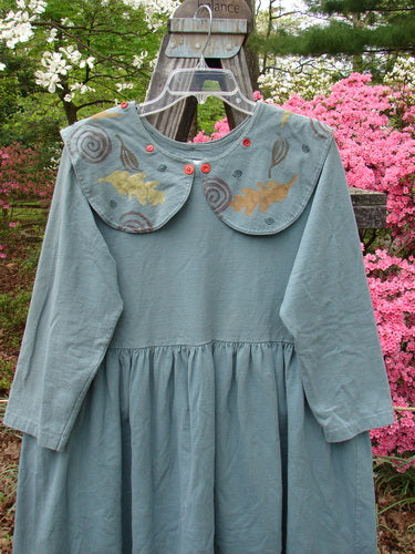 1992 Silly Collar Dress Spin Leaf Grey Green Size 1: A long, empire waist dress with a sailor collar and mismatched buttons, displayed on a swing.