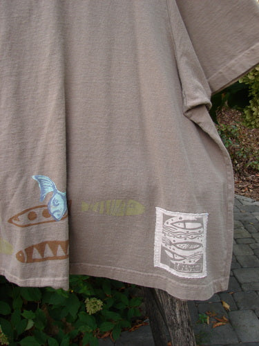 1999 Tiny Pocket Top Fishie Riverbed Size 2 features screen-printed fish designs along the hem, hanging outdoors. This cropped, organic cotton T-shirt showcases a swingy A-line shape and signature Blue Fish patch.