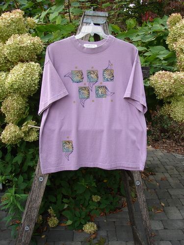 1997 Short Sleeved Tee Five Shell Jasmine Size 1 displayed on a wooden ladder, features a grid of shell motifs in greens and yellows, showcasing Bluefishfinder.com's vintage elegance and creativity.