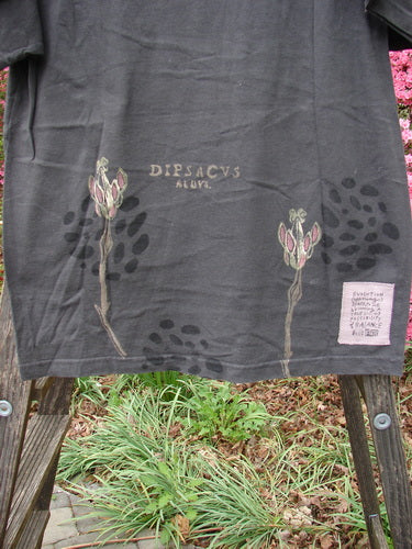 1998 Botanicals Short Sleeved Tee Triple Sprout Raven Size 0, featuring a colorful botanical design, ribbed neckline, and Blue Fish patch, displayed with a wooden plank and plants in the background.