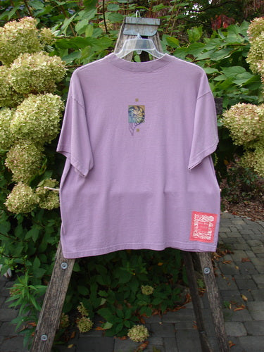 1997 Short Sleeved Tee Five Shell Jasmine Size 1, displayed on a wooden ladder outdoors, features a stylized face and sun motif on the back and a red-and-white label near the hem.