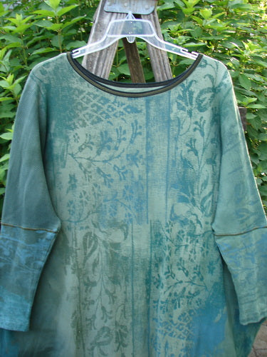 Barclay Thermal Contrast Revival Top Botanicals Green Storm OSFA displayed on a rack, highlighting its ribbed sleeves, rounded neckline, and unique A-line shape with a continuous botanical theme design.