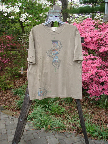 2000 Artist Choice Short Sleeved Tee Geo Dove Size 1 displayed on a clothes rack, showcasing its drop shoulders, slightly thinner rolled and ribbed neckline, and simplistic geometric design.