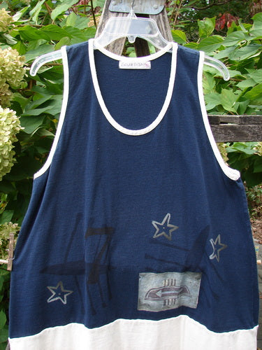 1998 8 Ball Tunic Games Crew Blue Size 1: A sleeveless navy-and-white tank with white trim, star motifs, rectangular patch, scoop neckline, and double-paneled hem, hanging outdoors amidst greenery.
