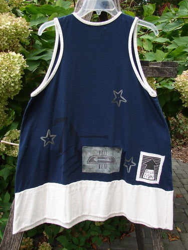 1998 8 Ball Tunic Games Crew Blue Size 1, a sleeveless tunic with navy and off-white sections, star motifs, and Blue Fish print, draped on a garden ladder amidst greenery.