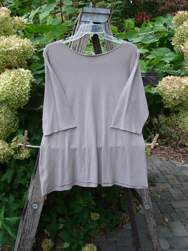 Barclay Batiste Raw Edge Layering Top Unpainted Stone Size 1 displayed on a wooden trellis, showcasing its wide raw-cut neckline, three-quarter sleeves, and rolled edges, embodying Bluefishfinder's vintage aesthetic.