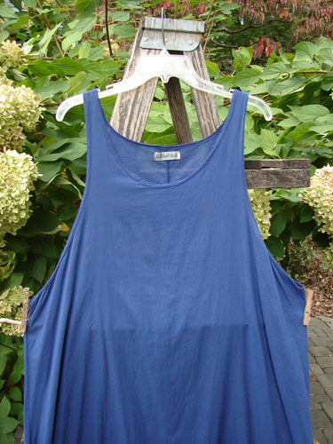 Barclay Batiste Side Gather Back Draw Shift Dress Unpainted Royal Blue Size 2 features a sleeveless, loose-fit, ankle-length design, displayed on a hanger against a garden backdrop, highlighting its seamless structure and adjustable gathers.