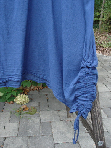 Barclay Batiste Side Gather Back Draw Shift Dress Unpainted Royal Blue Size 2 draped over a chair, showcasing its side ruched seam with a drawstring, highlighting its loose, seamless design.