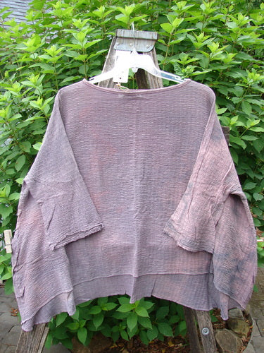 Barclay NWT Crinkle Gauze Top Mottled Smokey Rose Quartz OSFA displayed on a clothes rack, showcasing its wide, boxy cut, high-low hemline, and three-quarter dolman sleeves with frayed edges.