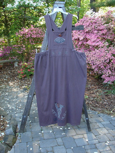 1995 Omega Jumper Magic Leaf Bloomsberry OSFA displayed on a wooden ladder, showcasing its stoneware buttoned front pocket, wide front bib, sectional panels, and double-layered waistband with apron-style look.