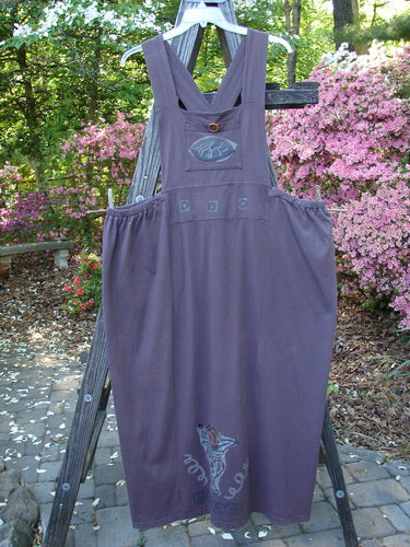 1995 Omega Jumper Magic Leaf Bloomsberry OSFA displayed on a wooden ladder, showcasing its wider front bib, stoneware buttoned front pocket, sectional panels, and apron-style look.