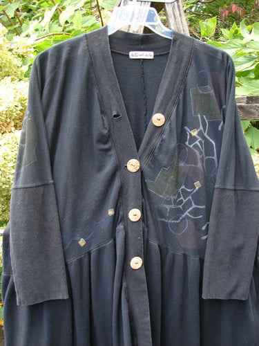 Barclay Thermal Bungalow Jacket in black with abstract graphics, featuring a deep V-neck, large wooden buttons, and a drapey knit fabric. The jacket has a unique scooped hemline and empire waist.