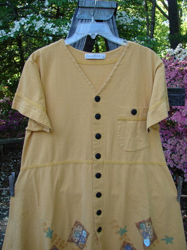 1998 Baseball Dress Games Lemonade Size 0 displayed on a hanger, featuring a deep V-neckline, dark buttons, paneled breast pocket, drop waist seam, and A-line lower sweep, made of mid-weight organic cotton.