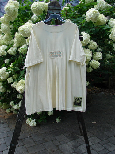 2000 Double Decker Pocket Top Pastel Fence Milk Size 2 displayed on a hanger, featuring two front oversized pockets, pleated back, and signature Blue Fish patch, made from organic cotton.