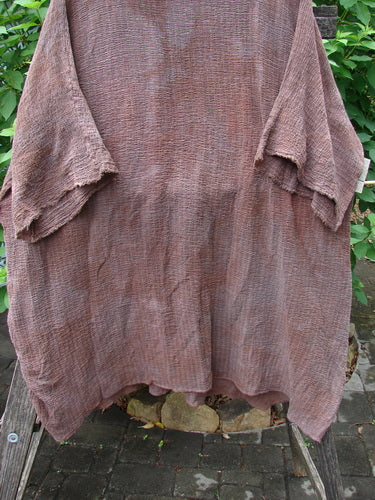 Barclay Crinkle Gauze Ana Tunic Dress in Mottled Copper displayed on a wooden post, showcasing its wide three-quarter sleeves, seamless shoulders, and varying hemline, highlighting its lightweight cotton gauze fabric.