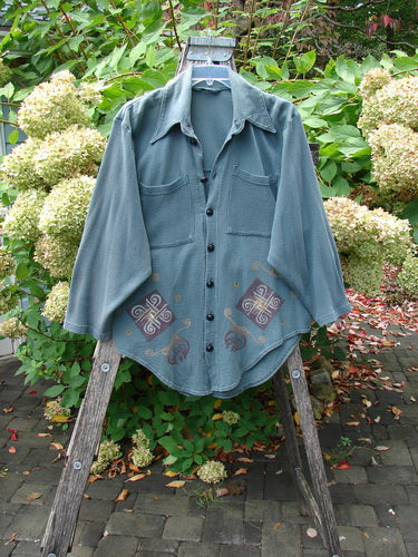 1996 Celtic Filias Jacket Celtic Loch Size 1, displayed on a wooden stepladder, showcases long sleeves, two chest pockets, decorative motifs, and shiny diamond-cut buttons, embodying Bluefishfinder.com's vintage aesthetic.