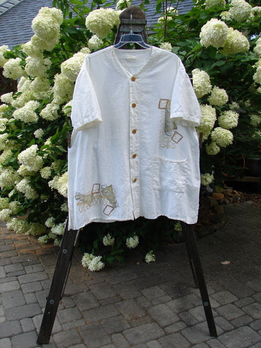 2000 Hemp Viscose Asymmetric Top Space White Size 1 with full button front, small V-neckline, tunic length, side vents, horizontal rear seam, and lower drop pocket displayed on a rack.