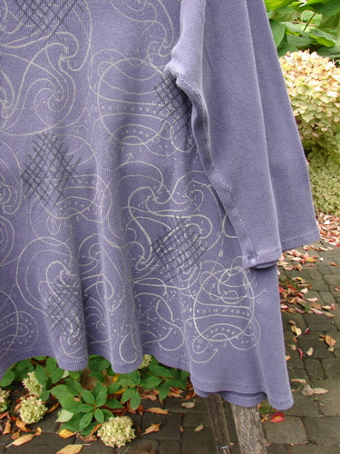 Barclay Thermal A Lined Top Spirograph Plum Size 2 draped on an outdoor bench, showcasing its swirling vine and lattice print, rounded neckline, cozy sleeves, and sweeping hemline in medium-weight cotton thermal.