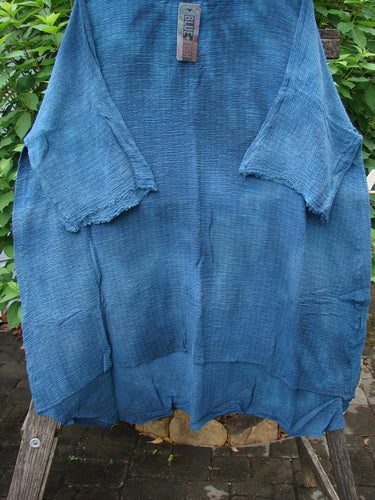 Barclay NWT Crinkle Gauze Ana Tunic Dress Unpainted Mottled Teal OSFA displayed on a wooden pole, showcasing its wide three-quarter sleeves, seamless shoulders, and varying hemline.