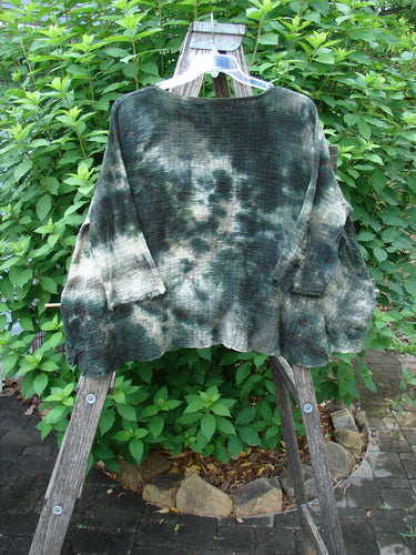 Barclay Crinkle Gauze Crop Top Mottled Forest Black Sky OSFA displayed on a wooden ladder, showcasing its wide boxy cut, high-low hemline, three-quarter dolman sleeves, and rolled neckline in featherweight gauze.