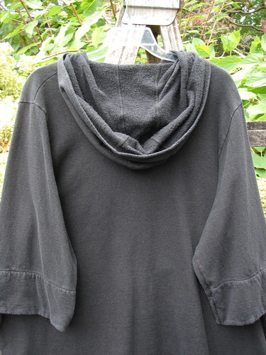 Barclay Fleece Single Button Hooded Jacket Grid Black Size 2, featuring wide sleeves and cozy hood, hangs outdoors against lush foliage, showcasing its smooth outer and textured inner fabric details.