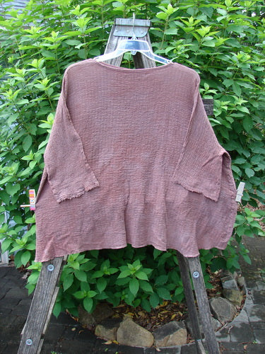 Barclay Crinkle Gauze Crop Top in Mottled Monrovian Clay displayed on a swinger. Features wide, boxy fit with three-quarter dolman sleeves and high-low hemline, epitomizing Blue Fish Clothing's creative vintage style.