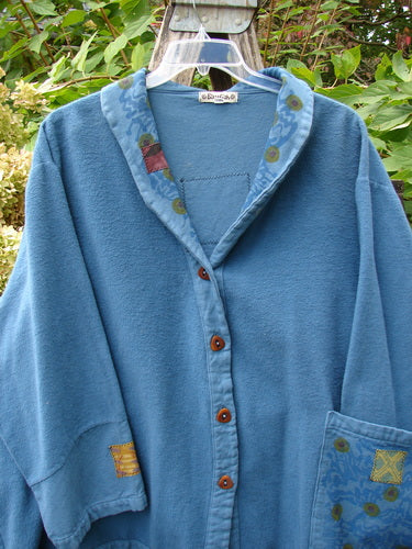 Barclay Patched Flannel Frolic Jacket Garden Blue Teal Size 2 hanging on a clear hanger outdoors, featuring wooden buttons, fabric patches on cuffs, appliqué collar detail, and oversized front pocket.